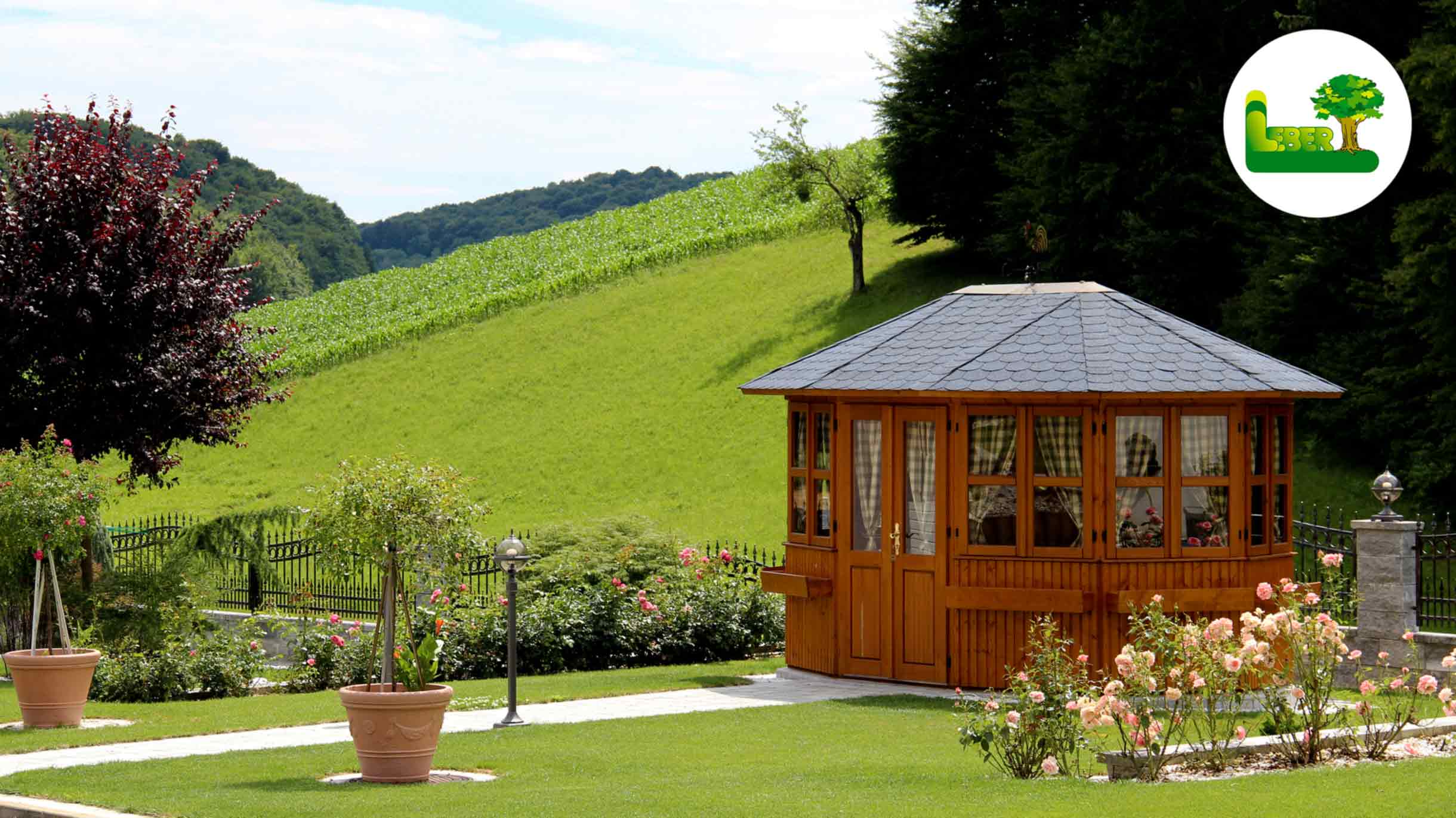 Holzpavillon mit Gartenweg und Bepflanzung. Im Hintergrund: Zaunstein Vesuv